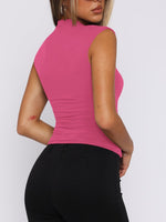 Person wearing a pink sleeveless top and black pants on a white background