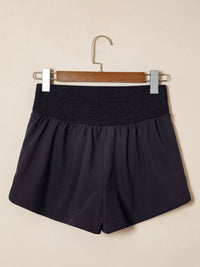 Black shorts on a hanger against a beige background