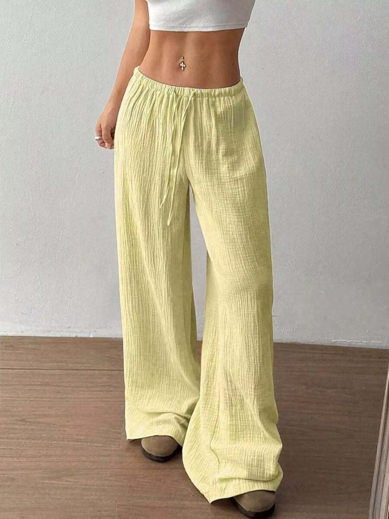 Person wearing light green wide-leg pants against a plain background