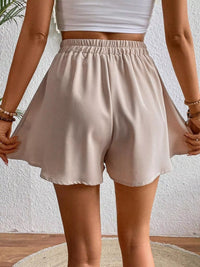 Beige shorts worn by a person against a neutral background