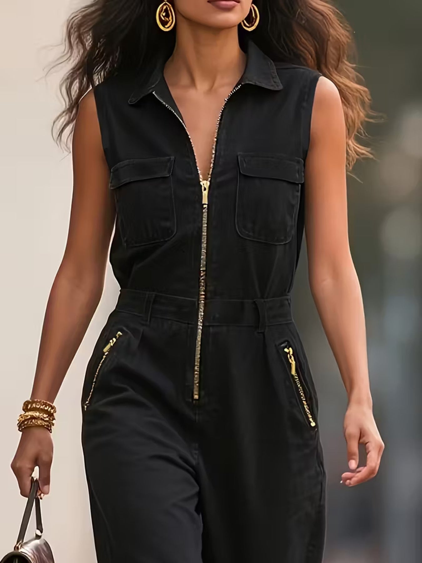 Woman wearing a black sleeveless jumpsuit with gold zippers against a blurred background
