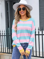 Woman wearing a colorful striped sweater and white hat outdoors.