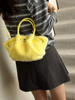 Person holding a yellow fluffy handbag with a striped shirt and black skirt.