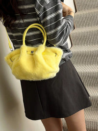 Person holding a yellow fluffy handbag with a striped shirt and black skirt.
