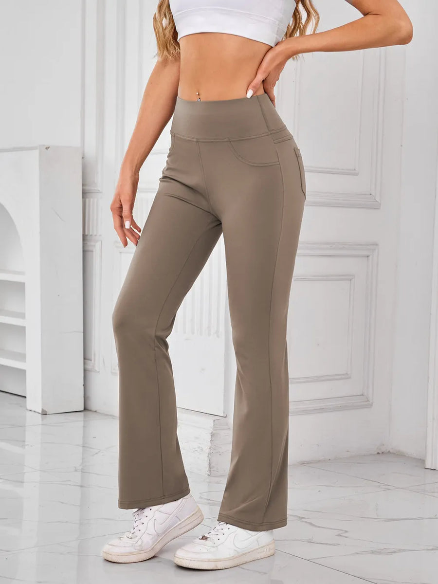 Person wearing beige flared pants and white sneakers in a minimalistic setting