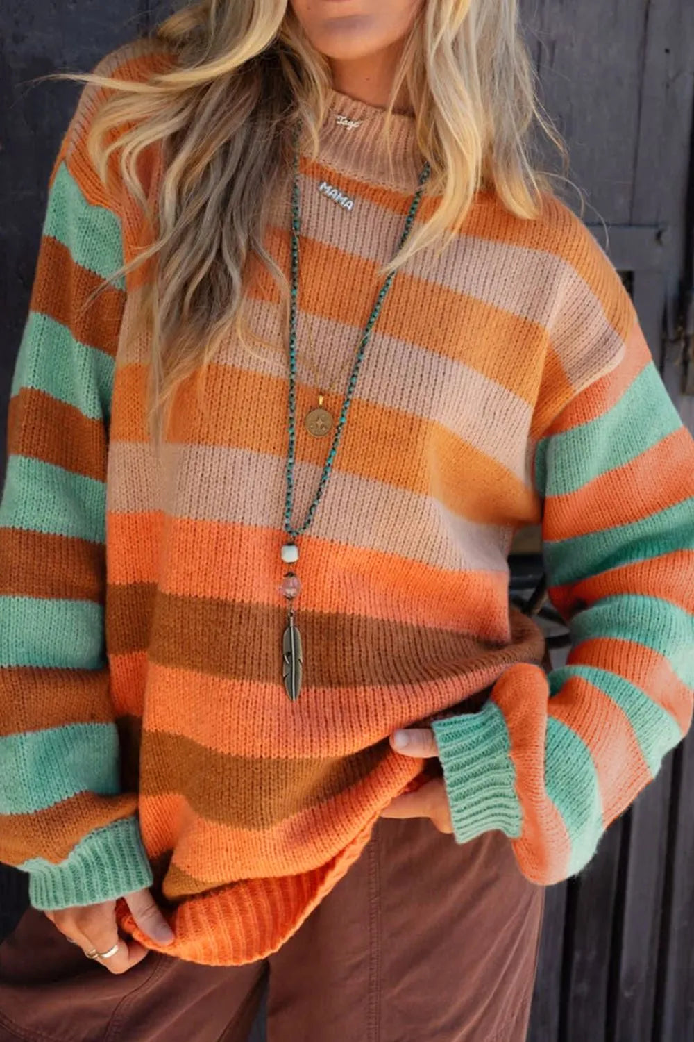 Person wearing a striped sweater with orange, green, and brown colors.