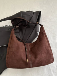 Brown leather handbag on a textured white surface