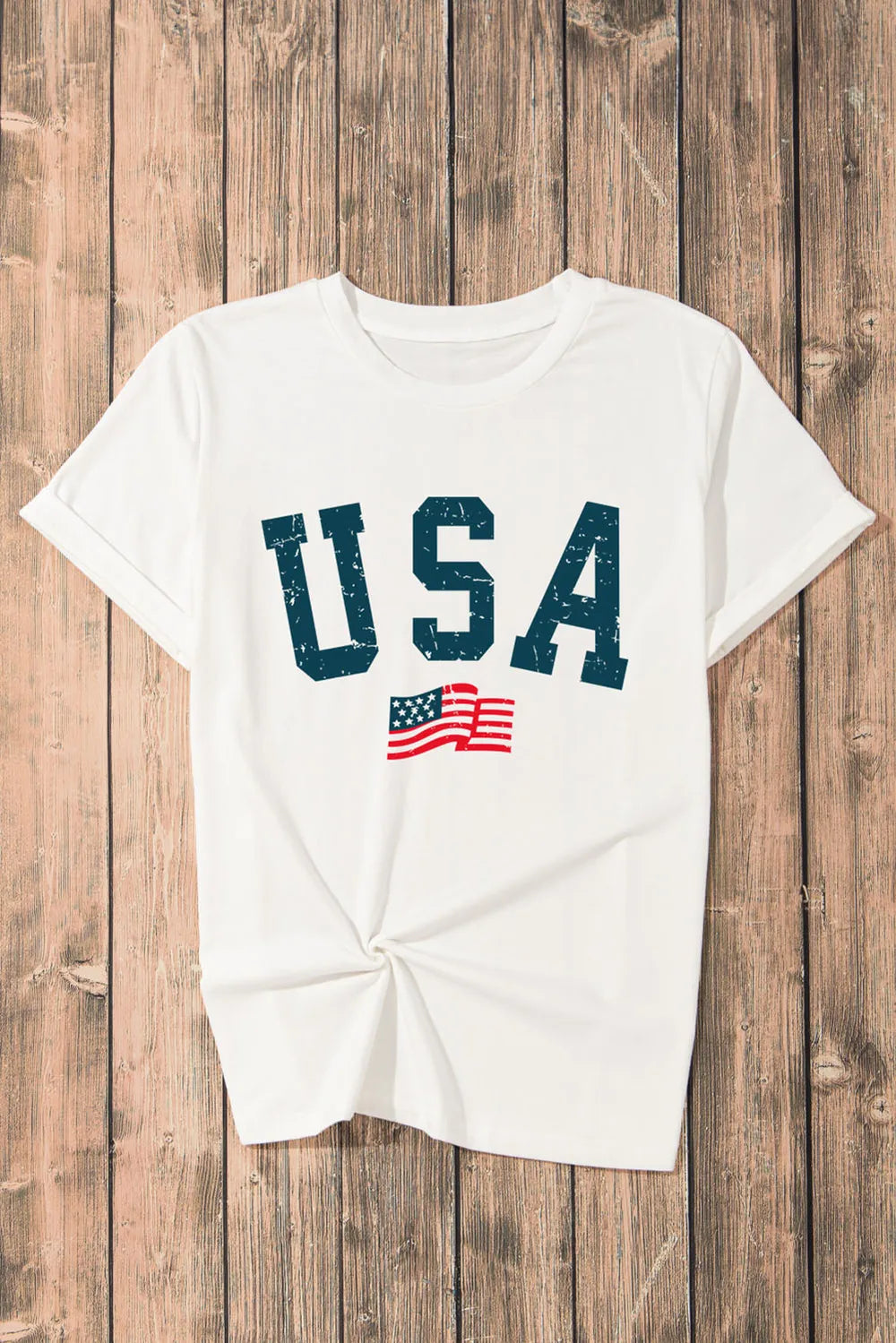 White t-shirt with 'USA' and American flag graphic on a wooden background