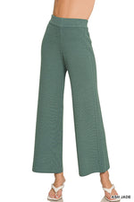 Green wide-leg pants worn by a person on a white background