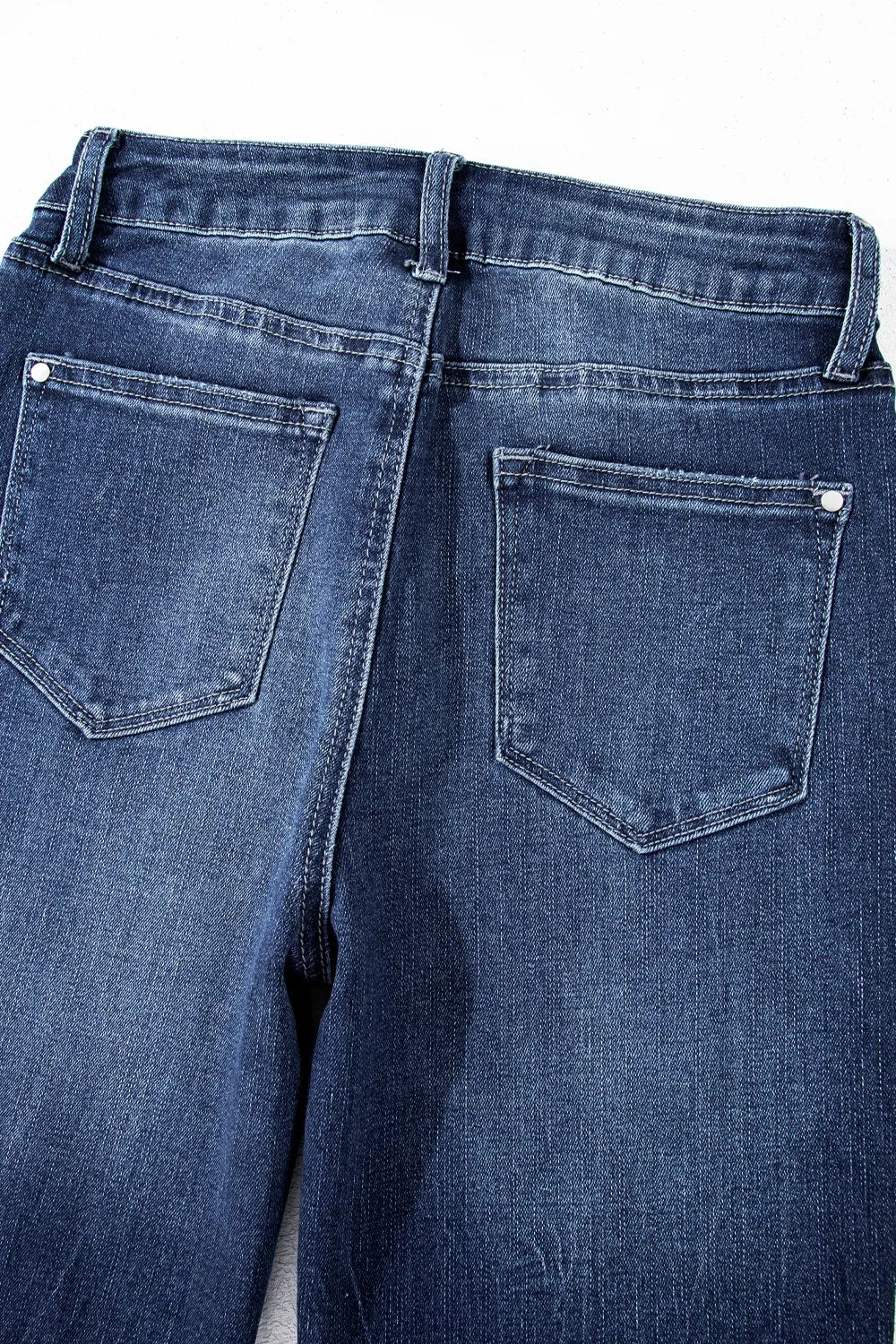 Close-up of blue jeans with a focus on the back pocket on a white background