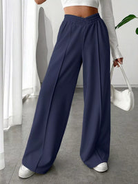 Person wearing navy wide-leg pants in a minimal indoor setting