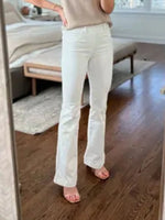 Person wearing light-colored jeans standing in a room with wooden flooring and a mirror.