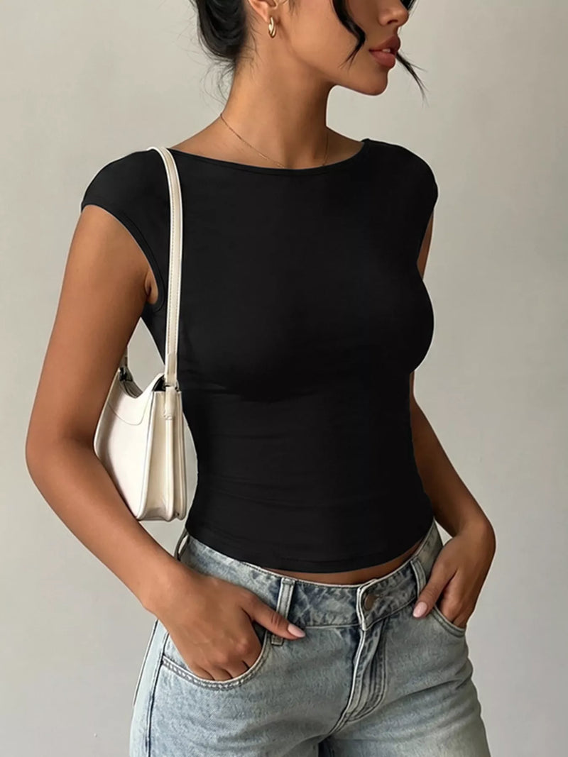 Woman wearing a black top and light blue jeans with a neutral background