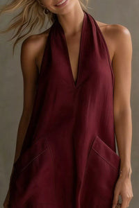 Woman wearing a burgundy halter neck dress against a neutral background