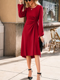 Woman in a red dress standing on a sidewalk with a cafe in the background