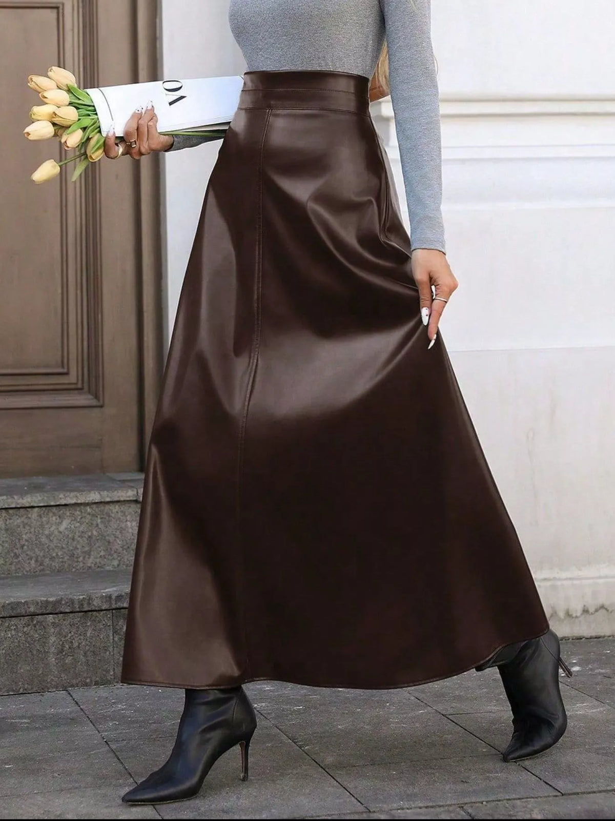 Person wearing a brown satin skirt holding tulips against a neutral background