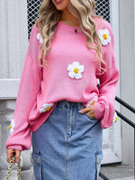 Person wearing a pink sweater with floral designs and blue jeans.