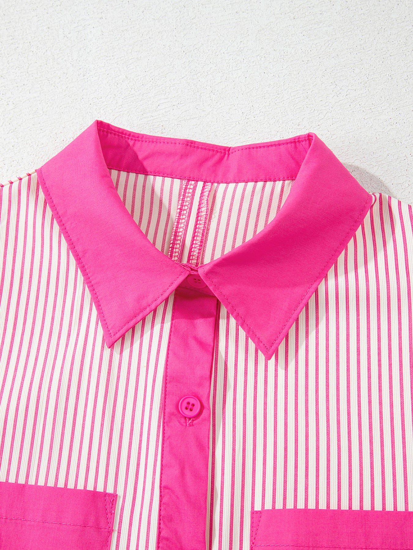 Close-up of a pink and white striped shirt with a bright pink collar on a light gray background