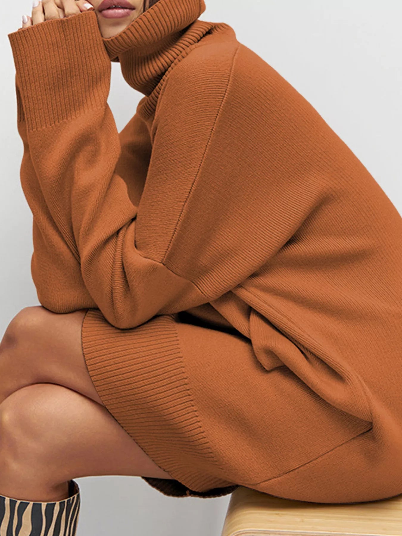 Person wearing a brown sweater with a plain background