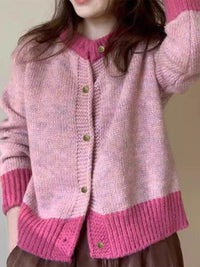 Person wearing a pink knitted cardigan with a plain background