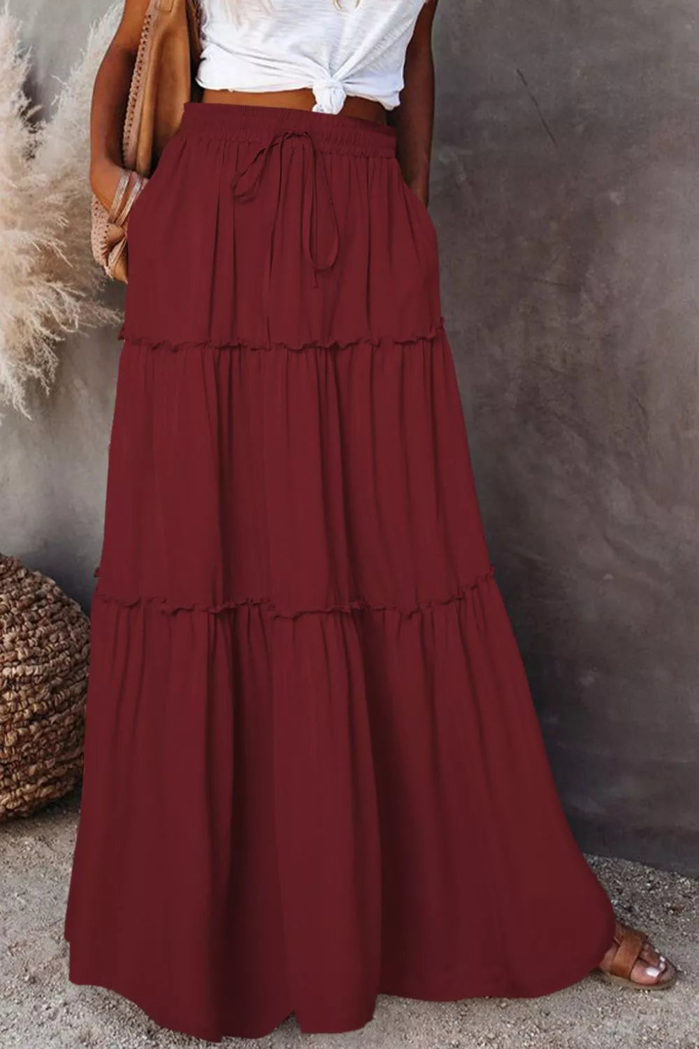Long burgundy skirt worn by a person against a neutral background