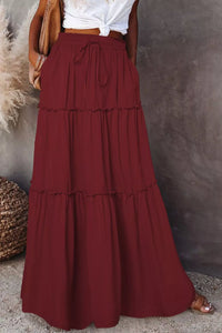 Long burgundy skirt worn by a person against a neutral background