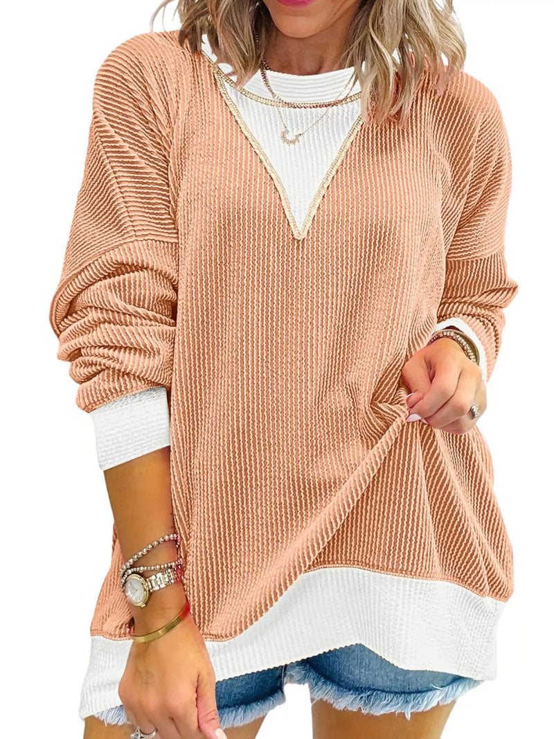 Woman wearing a beige sweater over a white shirt with denim shorts on a white background