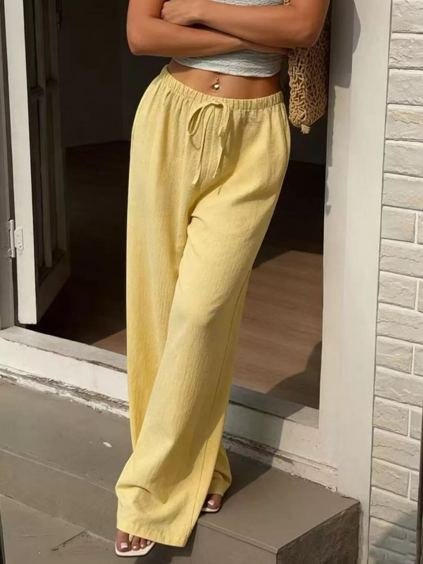 Person wearing yellow pants standing on a porch.