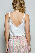 Person wearing a white lace camisole and floral skirt against a plain background