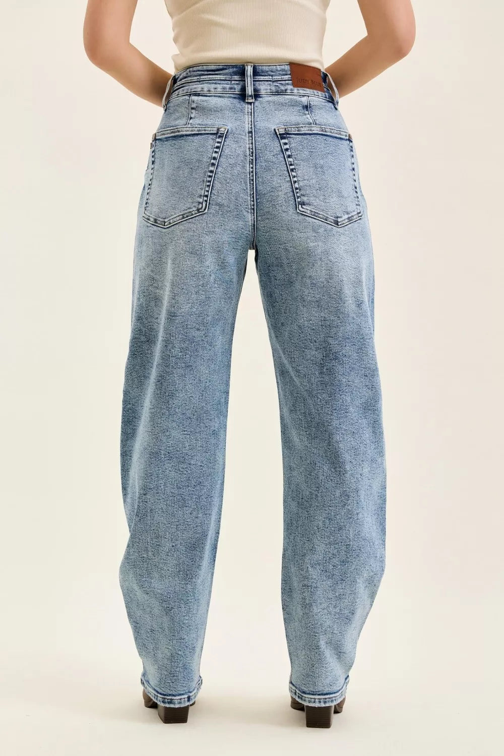 Light blue jeans worn by a person on a beige background