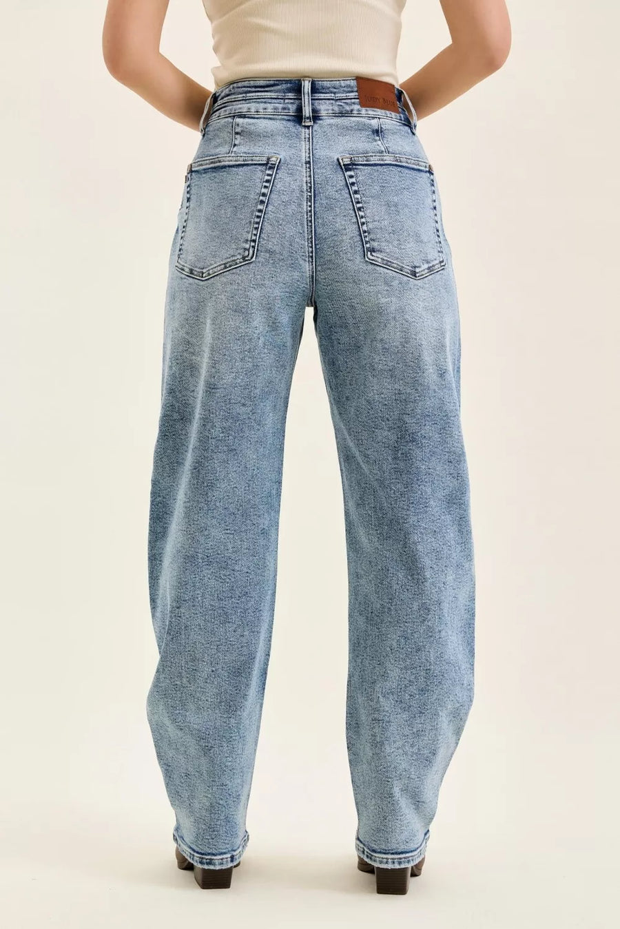 Light blue jeans worn by a person on a beige background
