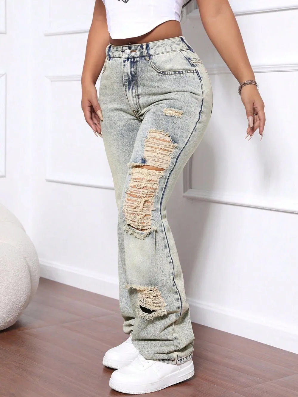 Person wearing light blue distressed jeans with a white background
