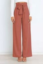 Cinnamon-colored wide-leg pants with a tie waist worn by a person on a white background
