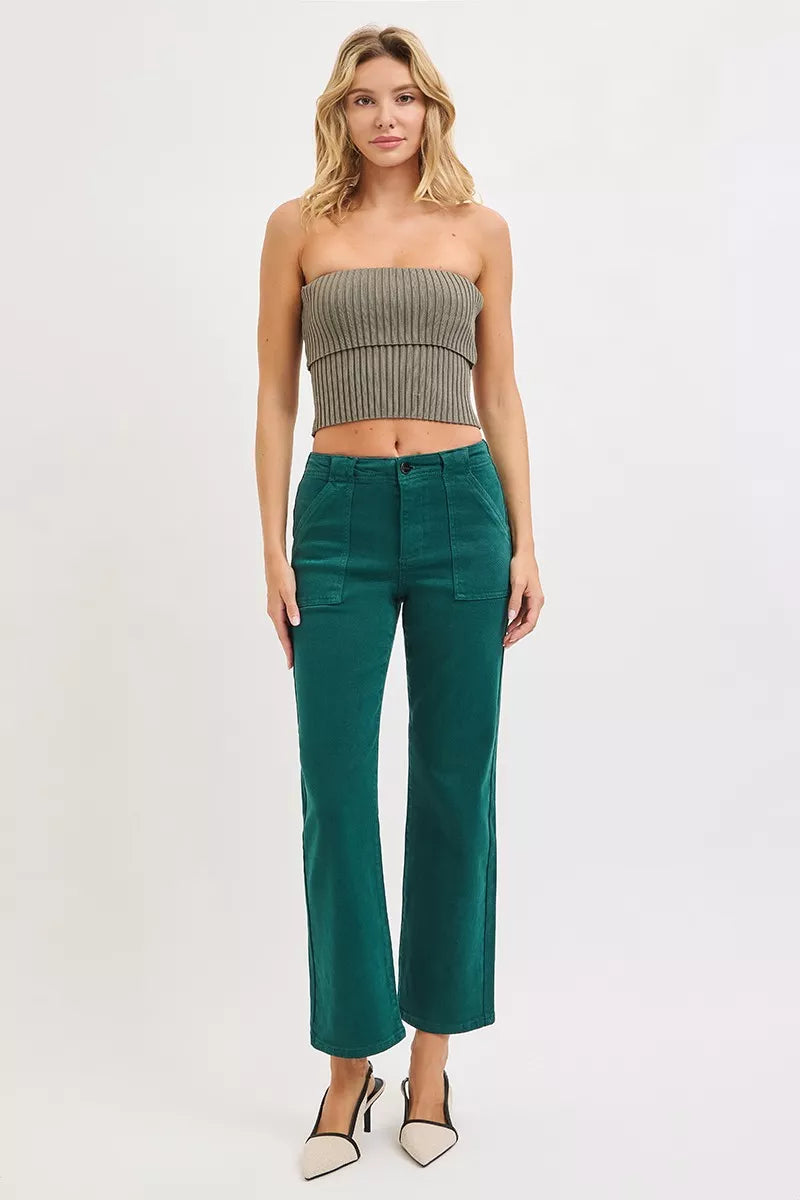 Woman wearing a strapless top and teal pants on a white background