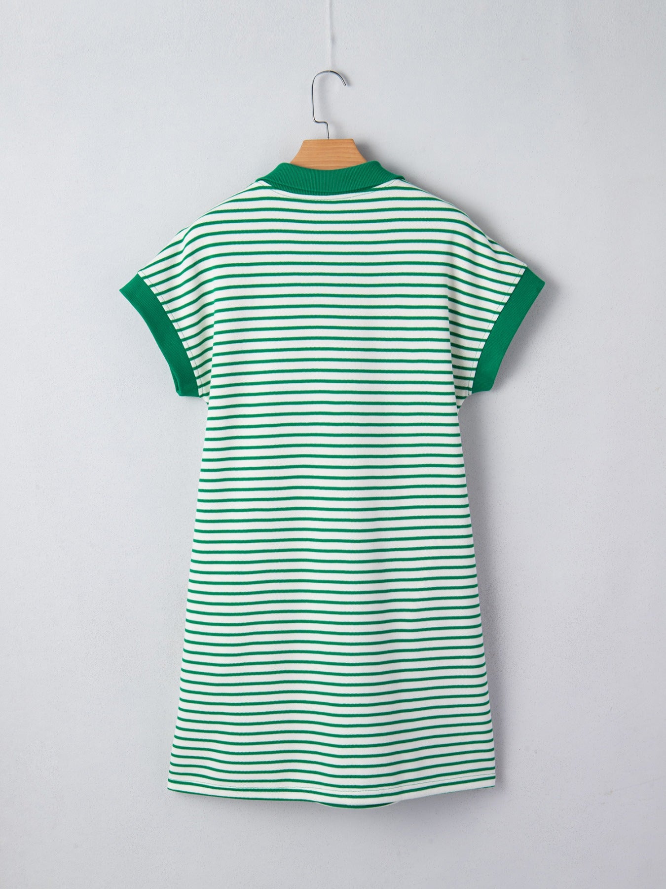Green and white striped dress on a hanger against a light gray background