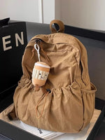 Brown backpack with a plush toy attached on a black surface