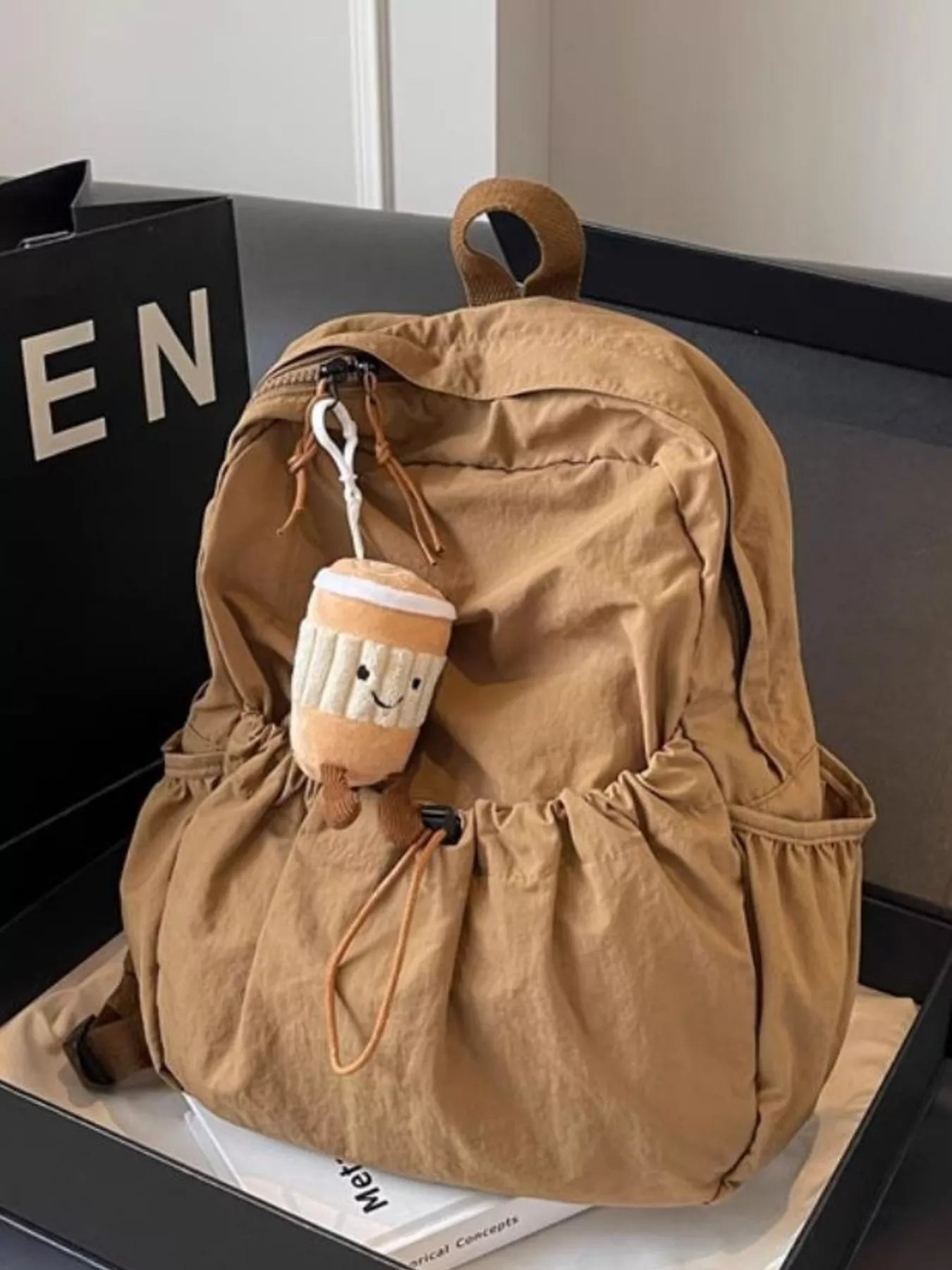 Brown backpack with a plush toy attached on a black surface