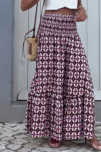 Person wearing a long patterned skirt with a white top and sandals, standing on a stone pavement.