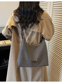 Person wearing a beige jacket with a gray backpack indoors.