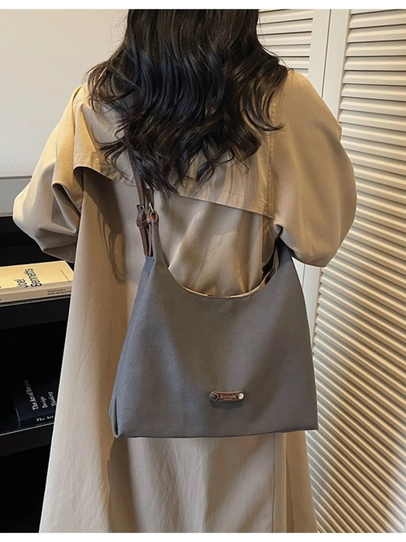 Person wearing a beige jacket with a gray backpack indoors.