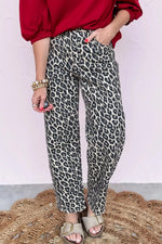 Person wearing leopard print pants with a red top and sandals on a textured surface.