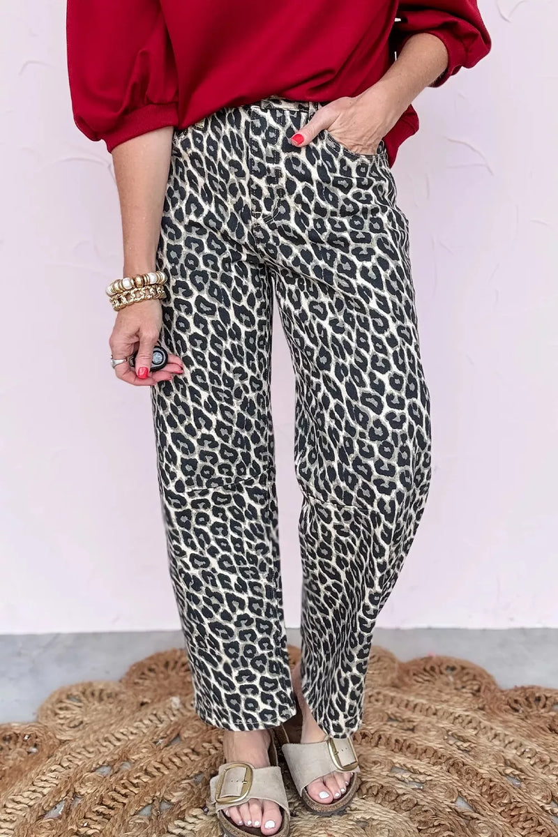 Person wearing leopard print pants with a red top and sandals on a textured surface.