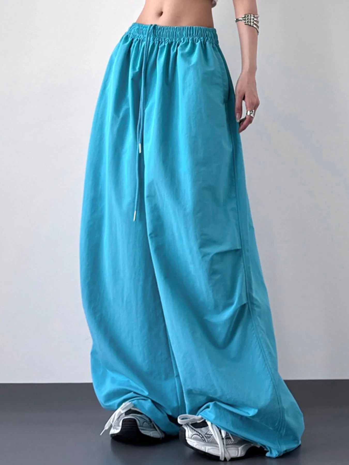 Turquoise wide-leg pants worn by a person on a gray background