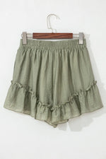 Green ruffled shorts on a hanger against a white background