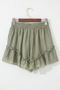 Green ruffled shorts on a hanger against a white background