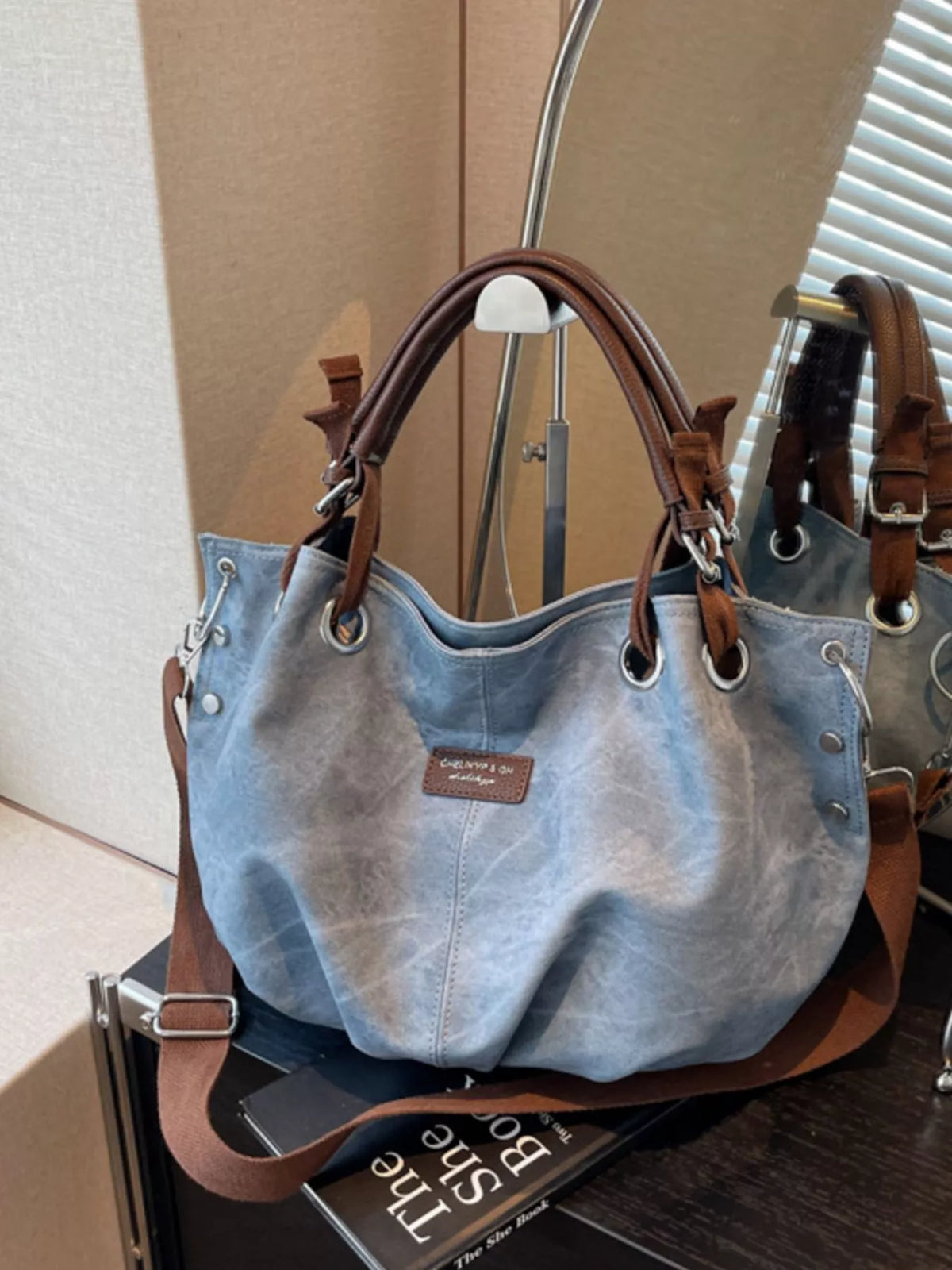 Blue handbag with brown handles and trim on a surface