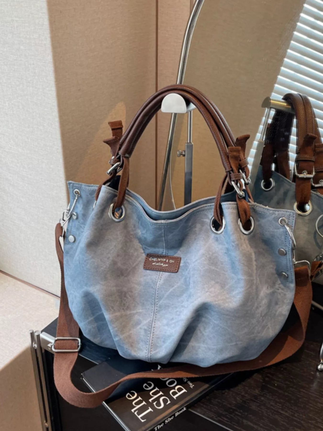 Blue handbag with brown handles and trim on a surface