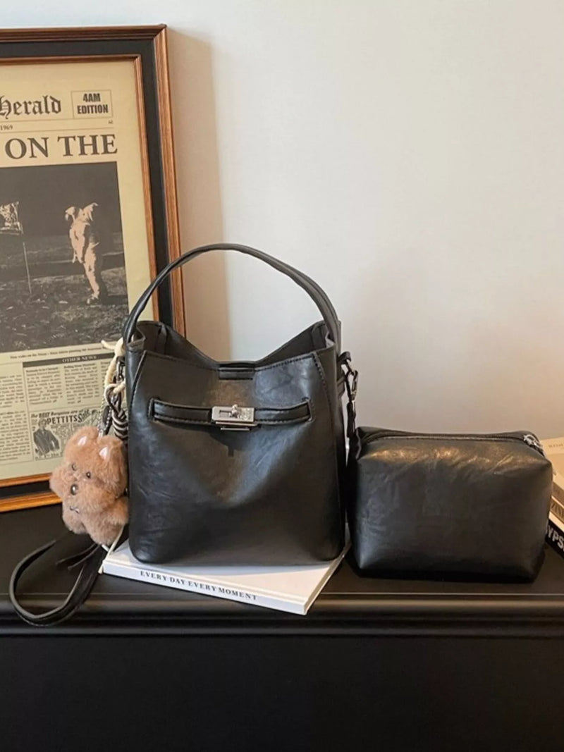 Black handbag and matching pouch on a surface with a newspaper in the background