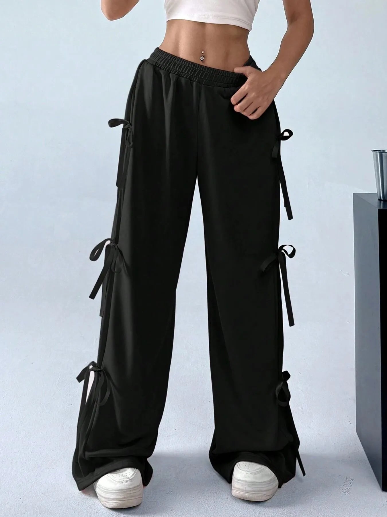 Black wide-leg pants with tie details worn by a person on a light gray background