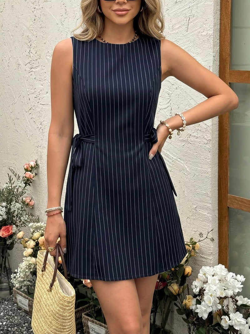 Woman wearing a navy pinstripe dress with a white background and decorative elements.